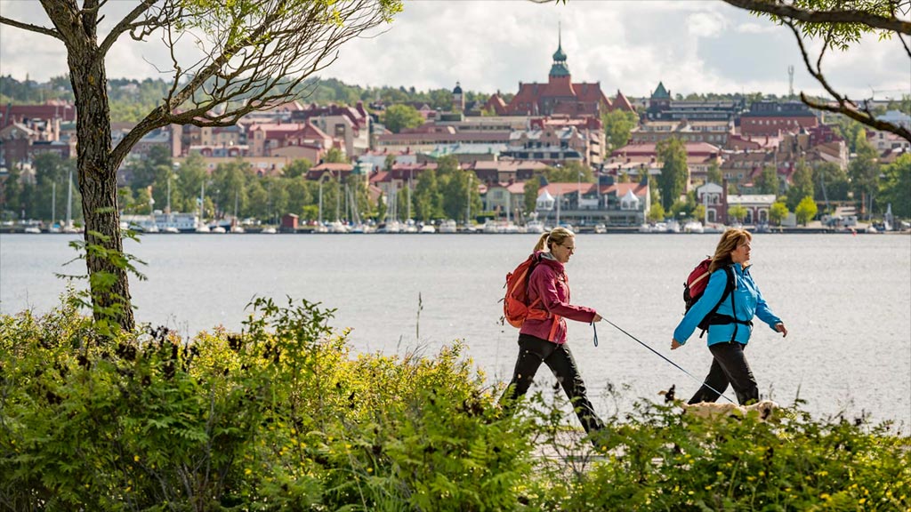 Två kvinnor som vandrar längs Storsjön. Östersund i bakgrunden.